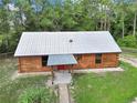Aerial view showcases cozy log cabin with metal roof and covered porch, set on a well-maintained lot at 5630 Se 183Rd Avenue Rd, Ocklawaha, FL 32179