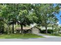 Exterior view of the house with mature trees, a well-kept lawn, and an attached garage at 1112 Ne 130Th Ter, Silver Springs, FL 34488
