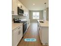 Bright kitchen with white cabinets, modern stainless steel appliances, and wood-look tile flooring at 13145 Sw 78Th Cir, Ocala, FL 34473