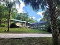 Inviting single-story home with a green metal roof, screened-in pool, and lush landscaping at 17051 Ne 243Rd Place Rd, Fort Mc Coy, FL 32134