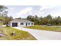 Charming single-story home featuring a modern exterior, a dark one-car garage, and a long concrete driveway at 23995 Nw Falcon Ave, Dunnellon, FL 34431