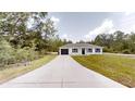 Charming single-story home featuring a modern exterior, a dark one-car garage, and a long concrete driveway at 23995 Nw Falcon Ave, Dunnellon, FL 34431