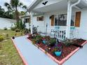 Inviting front porch with colorful flower beds, a well-maintained garden, and a cozy seating area at 8547 Sw 106Th Pl, Ocala, FL 34481