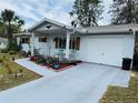 Beautiful single-story home with a manicured lawn, vibrant flower beds, and a freshly painted driveway at 8547 Sw 106Th Pl, Ocala, FL 34481