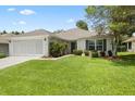 A lovely single-Gathering home features a well-kept lawn, a two-car garage and mature shrubbery at 11728 Se 91St Cir, Summerfield, FL 34491
