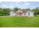 A charming single-story home with an attached garage and a well-maintained lawn provides inviting curb appeal at 144 Malauka Pass, Ocklawaha, FL 32179