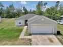 Exterior view of a charming single story home with a well-manicured lawn and an attached two-car garage at 15711 Sw 52Nd Avenue Rd, Ocala, FL 34473