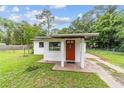 Charming single-story home featuring a red door, stucco siding, and a well-maintained front lawn at 2602 Ne 2Nd Ave, Ocala, FL 34470