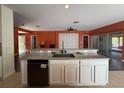 Kitchen island featuring granite countertop, white cabinetry, black dishwasher, and an open view to the living area at 3950 Sw 54Th Ct, Ocala, FL 34474