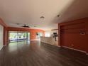 Open-concept living room with wood flooring, ceiling fan, and sliding glass doors leading to the outdoor living area at 3950 Sw 54Th Ct, Ocala, FL 34474