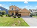Inviting two-story home featuring manicured lawn, tidy shrubbery, and neutral stucco exterior with an attached two car garage at 4094 Sw 51St Ct, Ocala, FL 34474