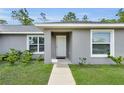 Close-up of the home's entrance, featuring a white front door, symmetrical windows, and verdant landscaping at 4501 Sw 159Th Street Rd, Ocala, FL 34473