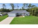 Inviting single-story home with a lush green lawn, long driveway, and an attached two-car garage at 4501 Sw 159Th Street Rd, Ocala, FL 34473