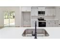 Modern kitchen with stainless steel appliances, white cabinets, and a sink overlooking the backyard at 5388 Nw 9Th St, Ocala, FL 34482
