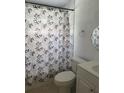 Well-lit bathroom with a leaf-patterned shower curtain and white fixtures at 6415 Ne 23Rd Ave, Ocala, FL 34479