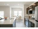 Modern kitchen with stainless steel appliances, granite countertops, and a breakfast bar overlooking the dining area at 6865 Sw 153 Place Rd, Ocala, FL 34473