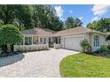 Charming single-story home featuring a brick driveway, manicured lawn, and attached two-car garage at 7242 Sw 115Th Pl, Ocala, FL 34476