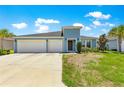 Charming light blue home boasting a well-manicured lawn and a spacious three-car garage, under a bright blue sky at 9209 Sw 58Th Cir, Ocala, FL 34476