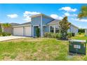 Charming light blue home boasting a well-manicured lawn and a spacious three-car garage, with lush green landscaping at 9209 Sw 58Th Cir, Ocala, FL 34476