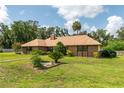 Brick home featuring mature trees, mulch beds and a well manicured lawn on a sunny day at 3555 Sw 24Th Avenue Rd, Ocala, FL 34471