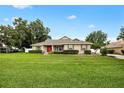 Inviting single story home with a well-maintained lawn and landscaped front yard, featuring a red front door at 4360 Se 106Th St, Belleview, FL 34420