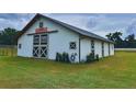 Well-maintained white barn featuring crossbuck doors, and the farm's name sign on the gable end at 7041 Ne 22Nd Court Rd, Ocala, FL 34479
