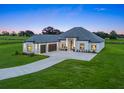 Expansive home featuring a modern design, well-lit exterior, and a long private driveway on lush green grounds at 7041 Ne 22Nd Court Rd, Ocala, FL 34479