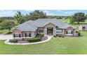 Landscaped front yard showcasing a lush lawn, mature plantings, and a one-story home with stone accents at 7220 Nw 83 Ter, Ocala, FL 34482