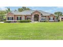 Manicured front yard featuring a sprawling lawn and a charming one-story home with elegant stone accents at 7220 Nw 83 Ter, Ocala, FL 34482