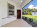 Welcoming screened front porch featuring a red front door, and trimmed landscape at 7707 Sw 94Th Cir, Ocala, FL 34481