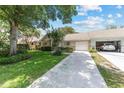 View of a single-story home with a well-manicured lawn and a driveway leading to an attached garage at 9065 Sw 82Nd Ter # G, Ocala, FL 34481