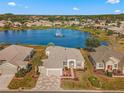 Stunning aerial view of a lakeside home with manicured lawn, lush landscaping, and a tranquil fountain at 9415 Se 125Th St, Summerfield, FL 34491