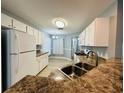 Spacious kitchen with white cabinetry, stainless steel sink, and laminate flooring leading to the dining area at 9706 Sw 92Nd Place Rd, Ocala, FL 34481