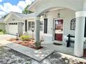 Inviting front porch with decorative columns, landscaping, and a red front door at 10130 Sw 61St Terrace Rd, Ocala, FL 34476