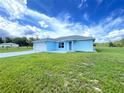 Charming single story home with blue siding, well manicured front lawn, and concrete driveway at 10758 Se Highway 464C, Ocklawaha, FL 32179