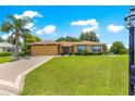Inviting home with a lush front lawn, mature landscaping, and a paved driveway leading to an attached garage at 13835 Se 85Th Cir, Summerfield, FL 34491