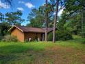 Side view of a one-story home with brown roof surrounded by a grassy yard and lush trees at 20045 Sw 88Th Place Rd, Dunnellon, FL 34431