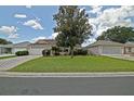 Inviting single-story home with manicured lawn, mature tree, and brick driveway at 3146 Williams Rd, The Villages, FL 32162