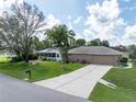 A home with an attached garage, well-maintained lawn, and mature trees providing shade at 5347 Pecan Rd, Ocala, FL 34472