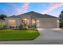 Charming one-story home at twilight features a manicured lawn and neutral stucco at 7243 Se 172Nd Legacy Ln, The Villages, FL 32162