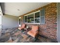 Relaxing front porch boasts tiled floors, comfortable chairs, and a brick accent wall for a cozy and welcoming entrance at 8461 Sw 109Th St, Ocala, FL 34481