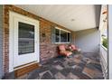 Inviting front porch features a tiled floor, comfortable seating, and a brick accent wall for a cozy outdoor space at 8461 Sw 109Th St, Ocala, FL 34481