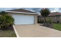Spacious driveway leading to a two-car garage, complemented by lush greenery at 9047 Sw 102Nd Cir, Ocala, FL 34481