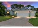 Charming single-story home with a well-manicured lawn and a three-car garage with lights on at 16023 Sw 14Th Avenue Rd, Ocala, FL 34473