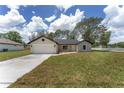 Inviting one-story home with a fresh exterior, long driveway, and green lawn at 26 Water Track Dr, Ocala, FL 34472