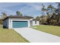 Single-story home with a blue garage door, a long concrete driveway, and lush green lawn at 3325 Sw 165Th Loop, Ocala, FL 34473