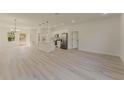 Spacious living room with light wood floors leading to a modern, all-white kitchen at 3325 Sw 165Th Loop, Ocala, FL 34473