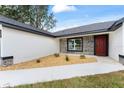 Inviting front entrance with stone accents, a red door, and decorative landscaping at 36 Pine Radl, Ocala, FL 34472