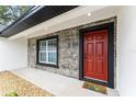 Close-up of front entrance with red door and stone features at 36 Pine Radl, Ocala, FL 34472