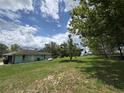 View of a single-story home with a stone facade, a propane tank and a lush green backyard at 6773 Se 87Th St, Ocala, FL 34472